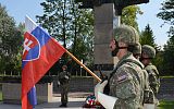 Składanie wieńców przy pomniku, na pierwszym planie żołnierze z flagą Słowacji