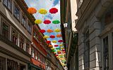 uliczka w Erfurcie, widok na niebo i zawieszone pomiędzy kamieniczkami kolorowe parasolki
