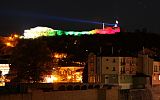 nocny widok na miasto, podświetlone budynki. Nad miastem góruje twierdza, oświetlona w kolorach flagi Bułgarii: białym, zielonym i czerwonym