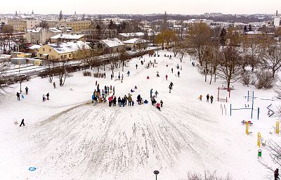 Zjazd dzieci z górki pokrytej śniegiem.