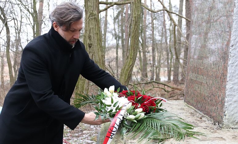 Prezydent Krystian Kinastowski składa wiązankę z biało-czerwonych kwiatów przed pomnikiem