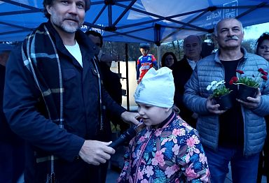 Prezydent Krystian Kinastowski trzyma mikrofon, do którego odpowiada dziecko