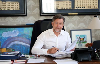 Prezydent Krystian Kinastowski w białej koszuli siedzi za biurkiem i podpisuje dokumenty