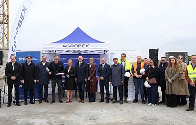 Kilkanaście osób pozuje do zdjęcia, to uczestnicy uroczystości wmurowania aktu erekcyjnego pod budowę nowych mieszkań